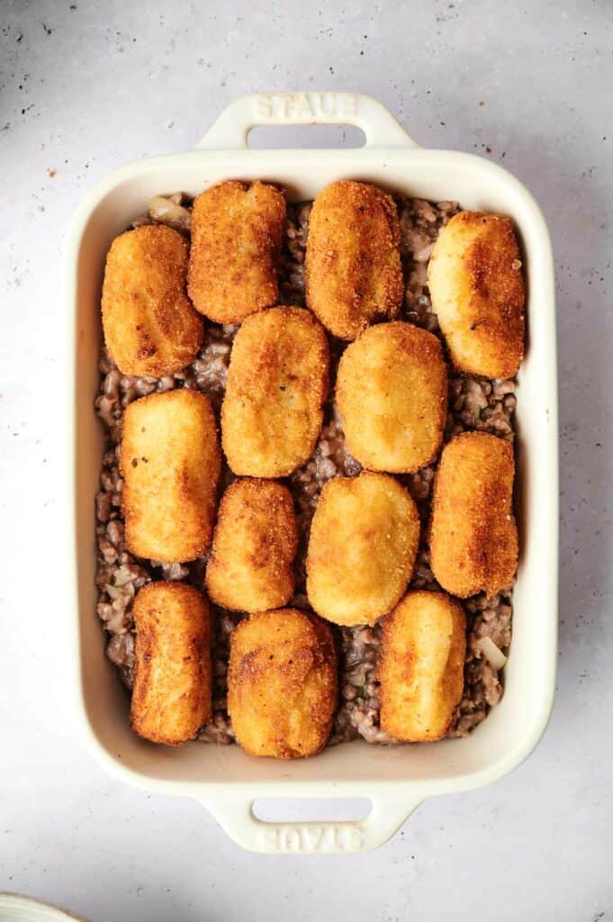 A tater tot casserole in a white baking dish.