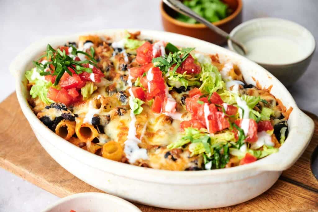 Walking taco casserole in a white dish with toppings.