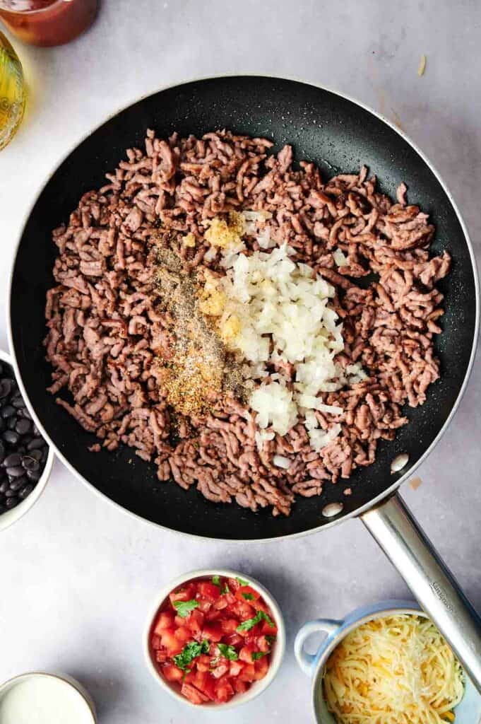 A skillet with ground beef, onion, and garlic.