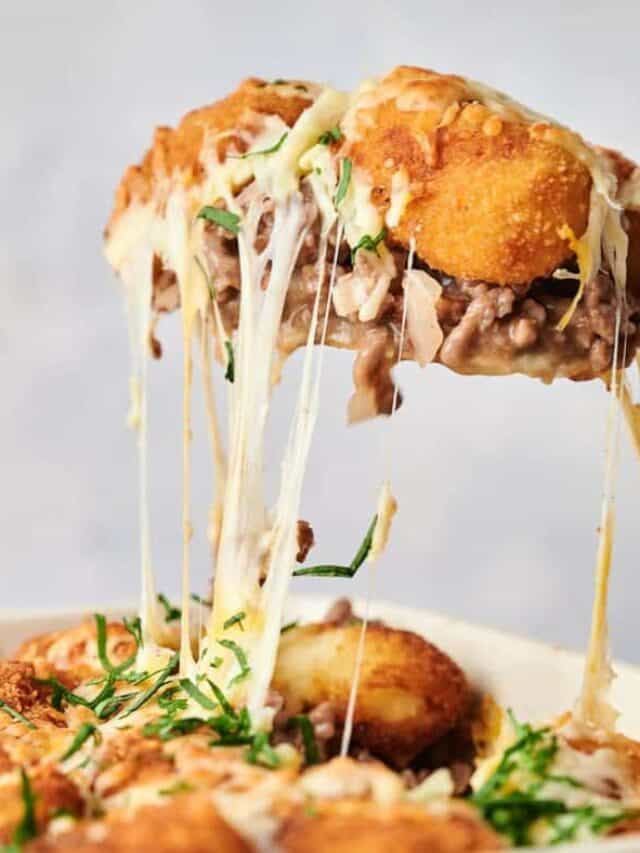 A close-up image of a cheesy mushroom burger with a crispy chicken patty, showcasing melted cheese being pulled apart.