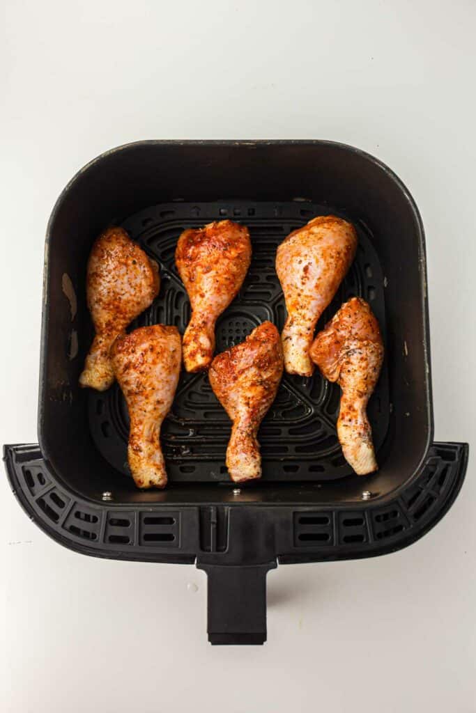 An air fryer pan with chicken drumsticks.