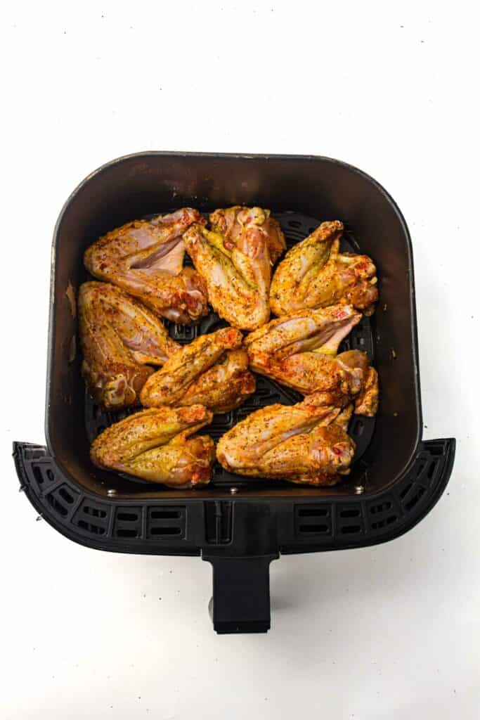 An air fryer pan with chicken wings in it.