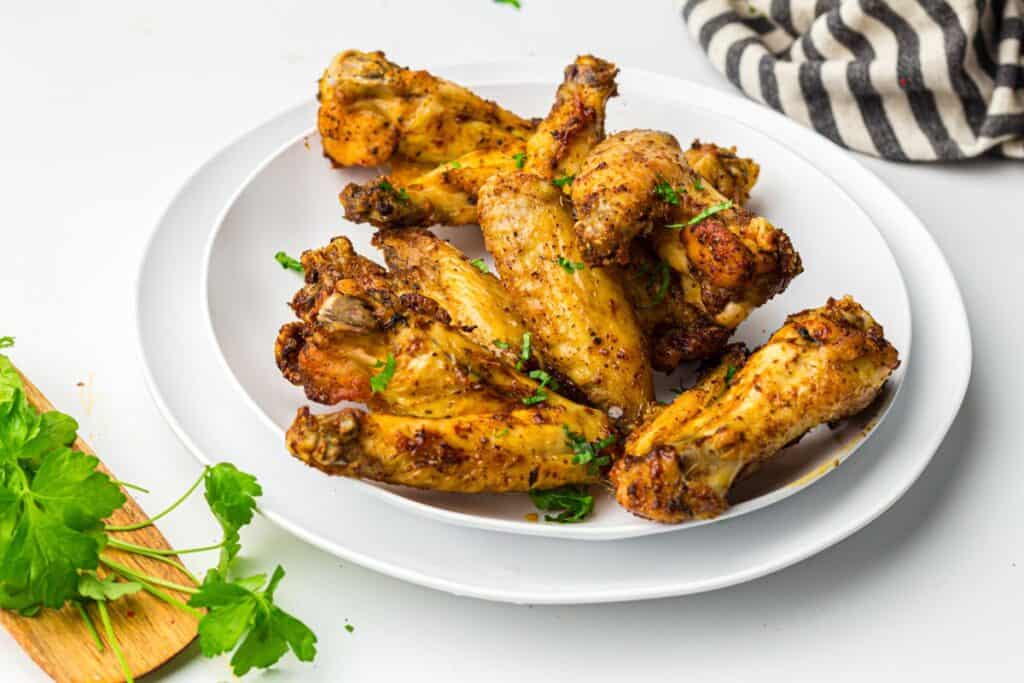 Air fryer chicken wings served on a white plate garnished with parsley.