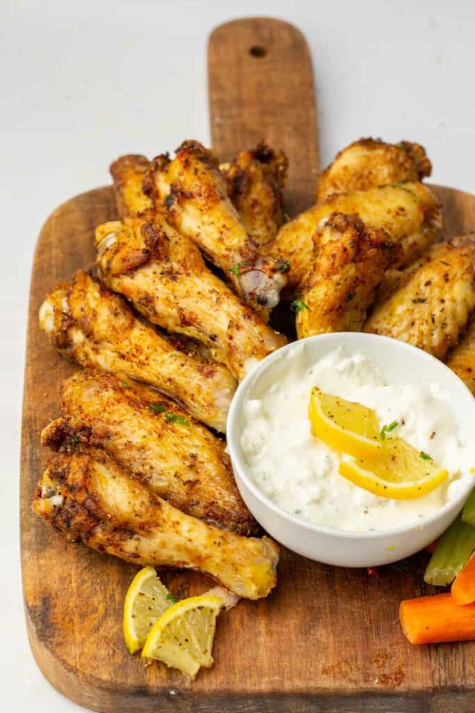 Air fryer chicken wings served on a wooden cutting board with dip.
