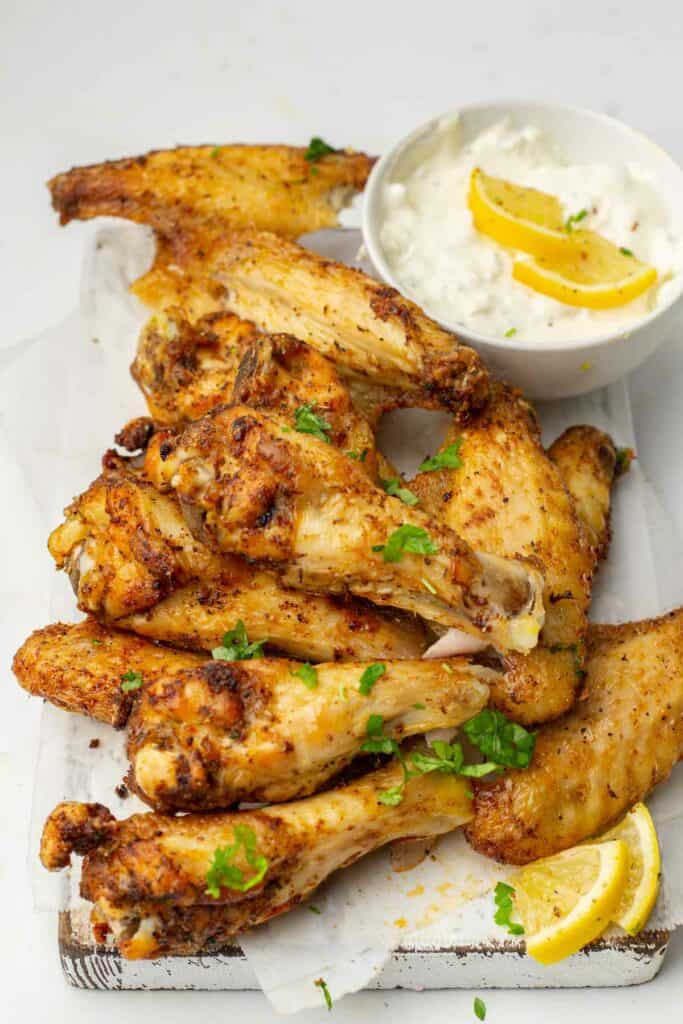 Air fried chicken wings on a cutting board with lemon wedges, perfect for a quick meal.