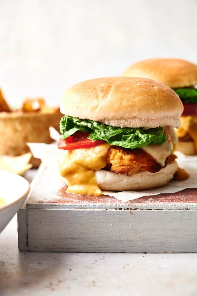 Two Zinger chicken burgers on a wooden cutting board.