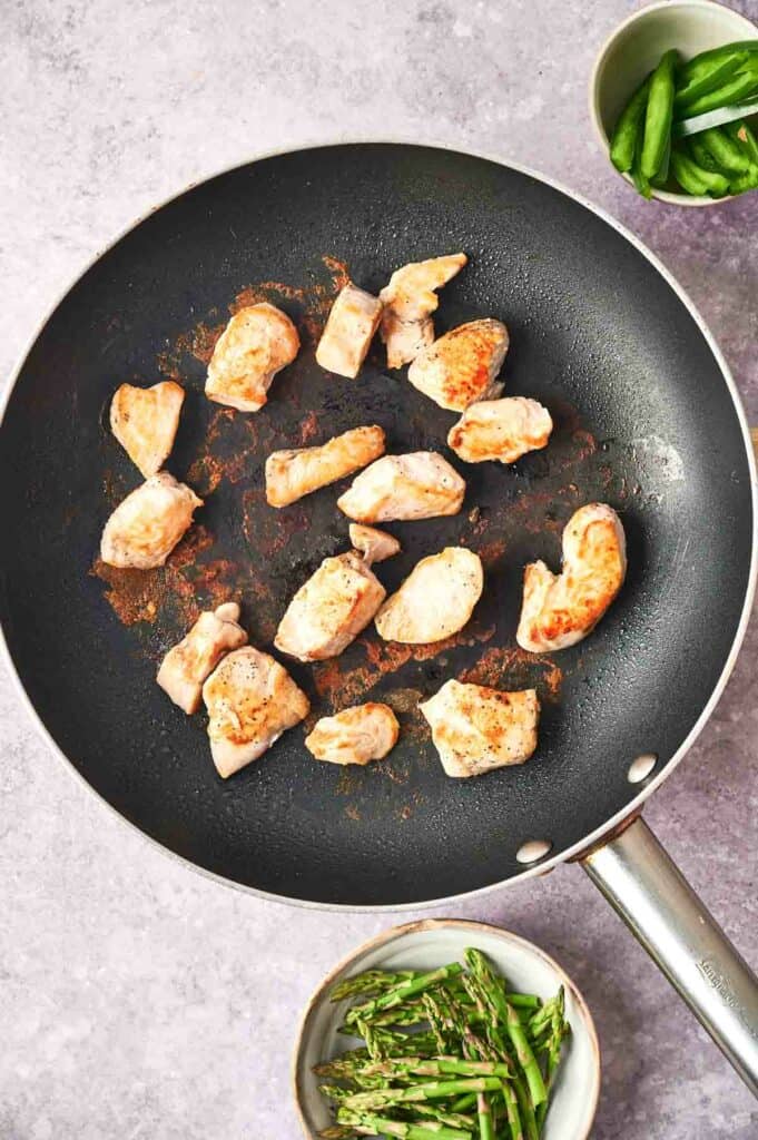 Chicken sizzling in a frying pan.