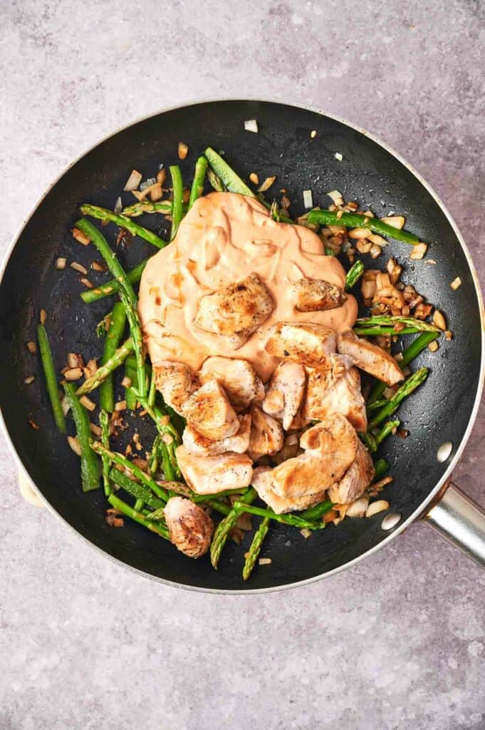 A frying pan with chipotle pasta and green beans.