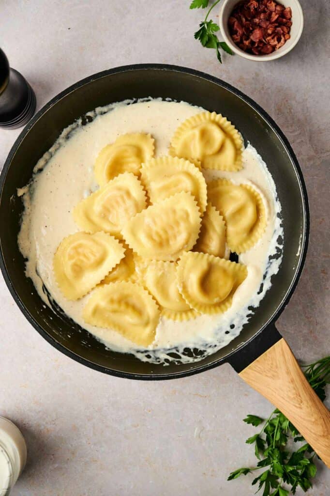 Freshly cooked Ravioli in a frying pan with cheese and herbs, reminiscent of Olive Garden's famous Ravioli Carbonara.
