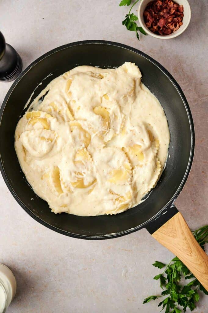 A pan of pasta with white sauce, for a ravioli carbonara recipe.