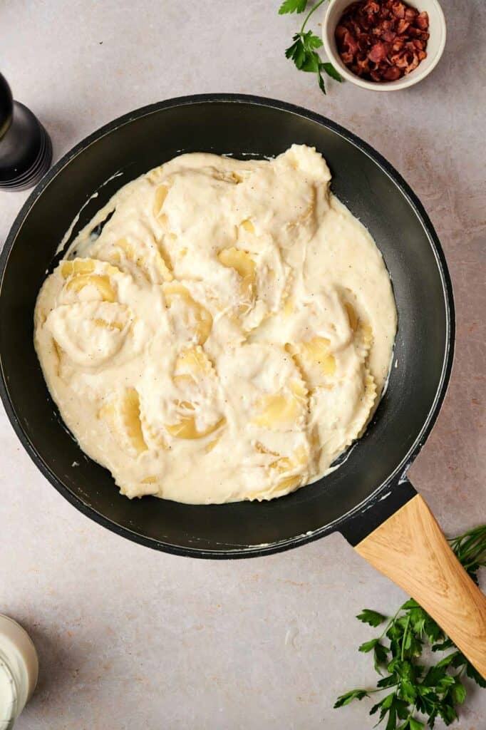 A pan of pasta with white sauce, for a ravioli carbonara recipe. 