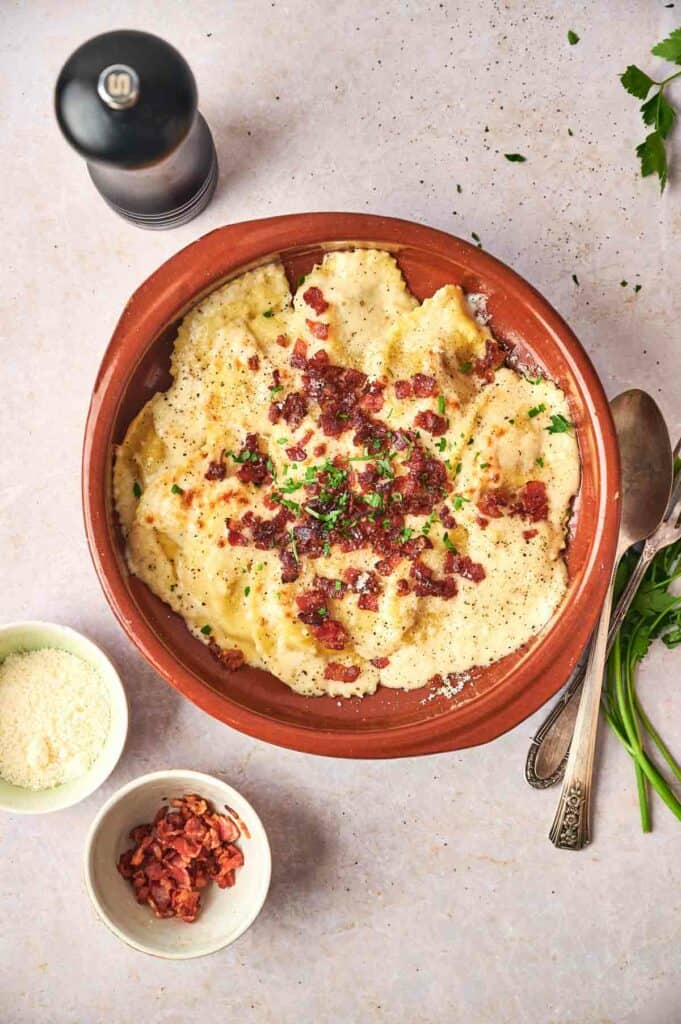A dish of Olive Garden ravioli with bacon and parmesan cheese.