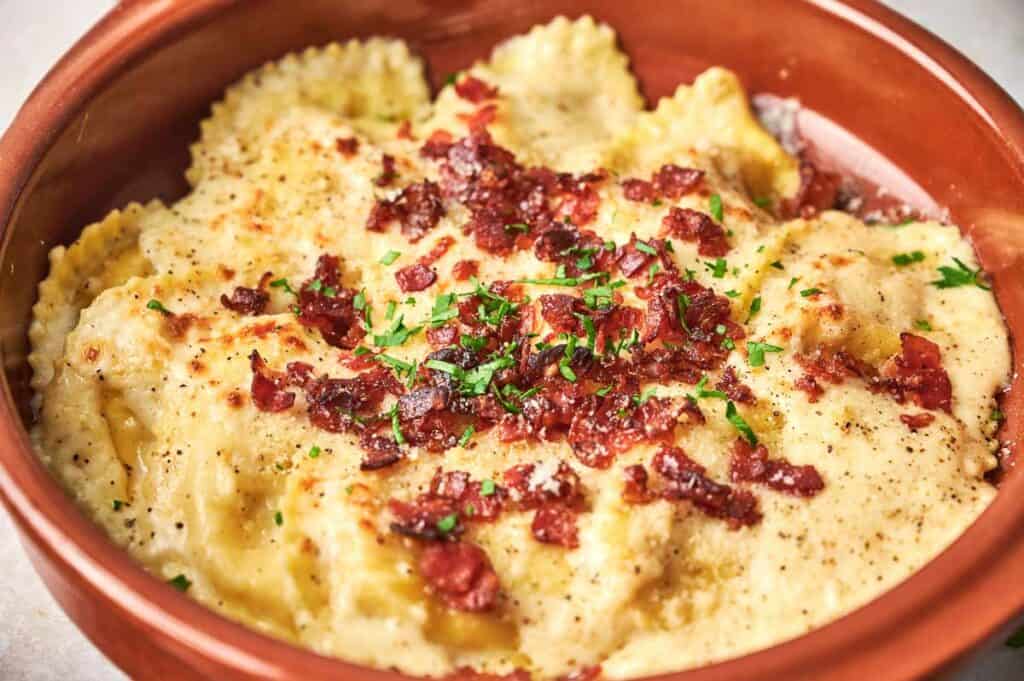 A dish of Olive Garden ravioli with bacon and parmesan cheese.
