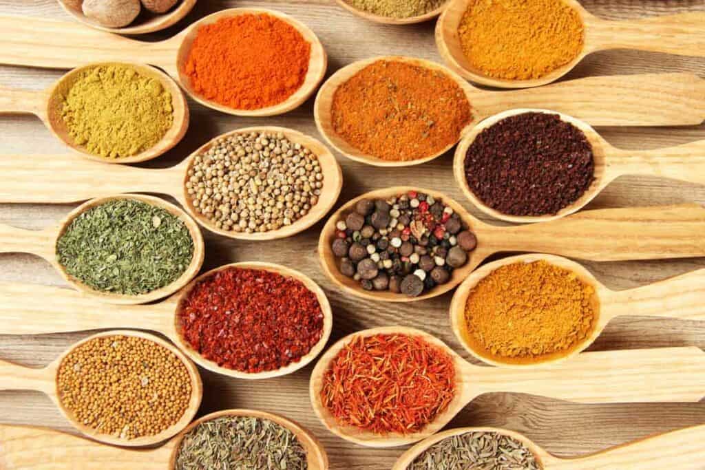 Many different types of spices in wooden spoons.