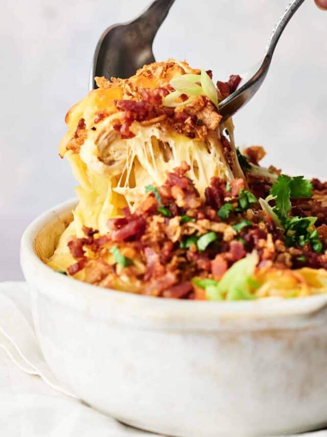 A person holding a fork over a chicken casserole dish.