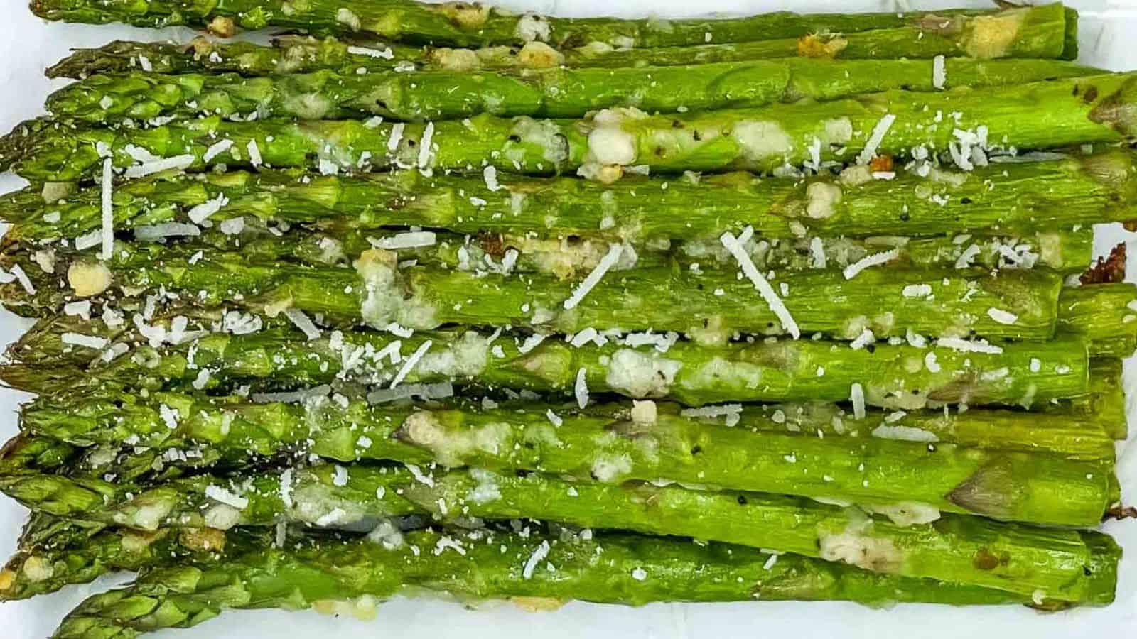 An air fryer pile of asparagus with grated cheese.