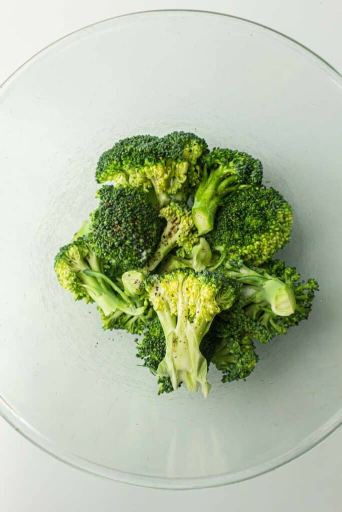 A bowl of fresh broccoli florets on a white background.