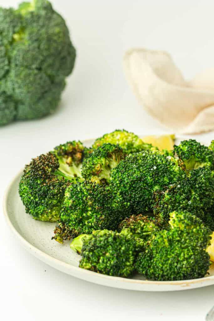 A plate of air-fried broccoli florets on a white background.