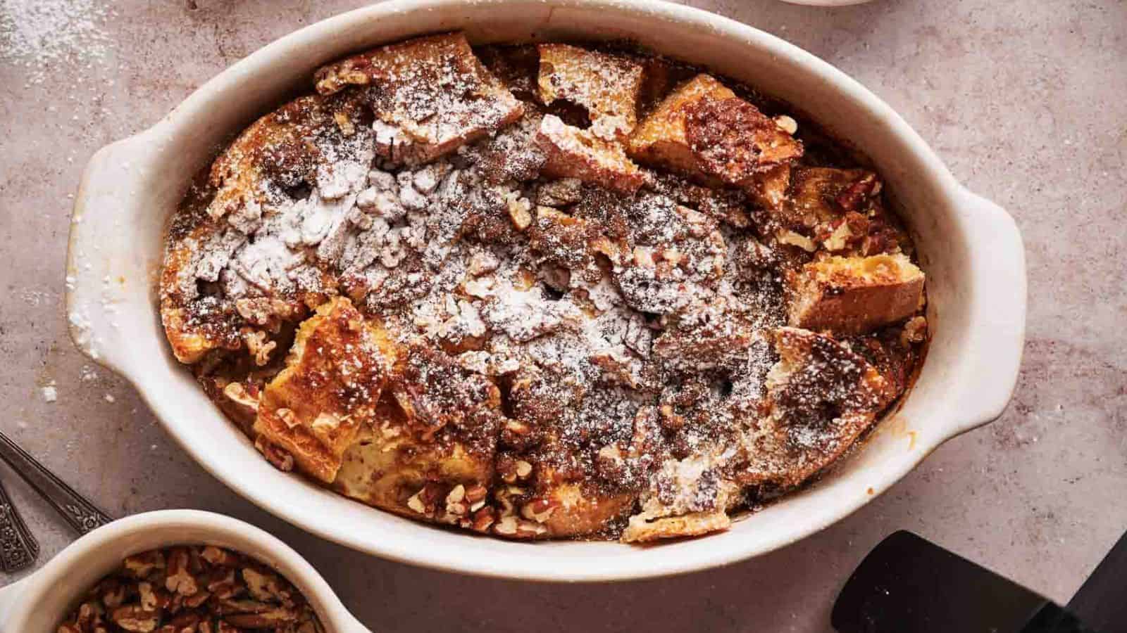 A dish of French toast with pecans and powdered sugar.
