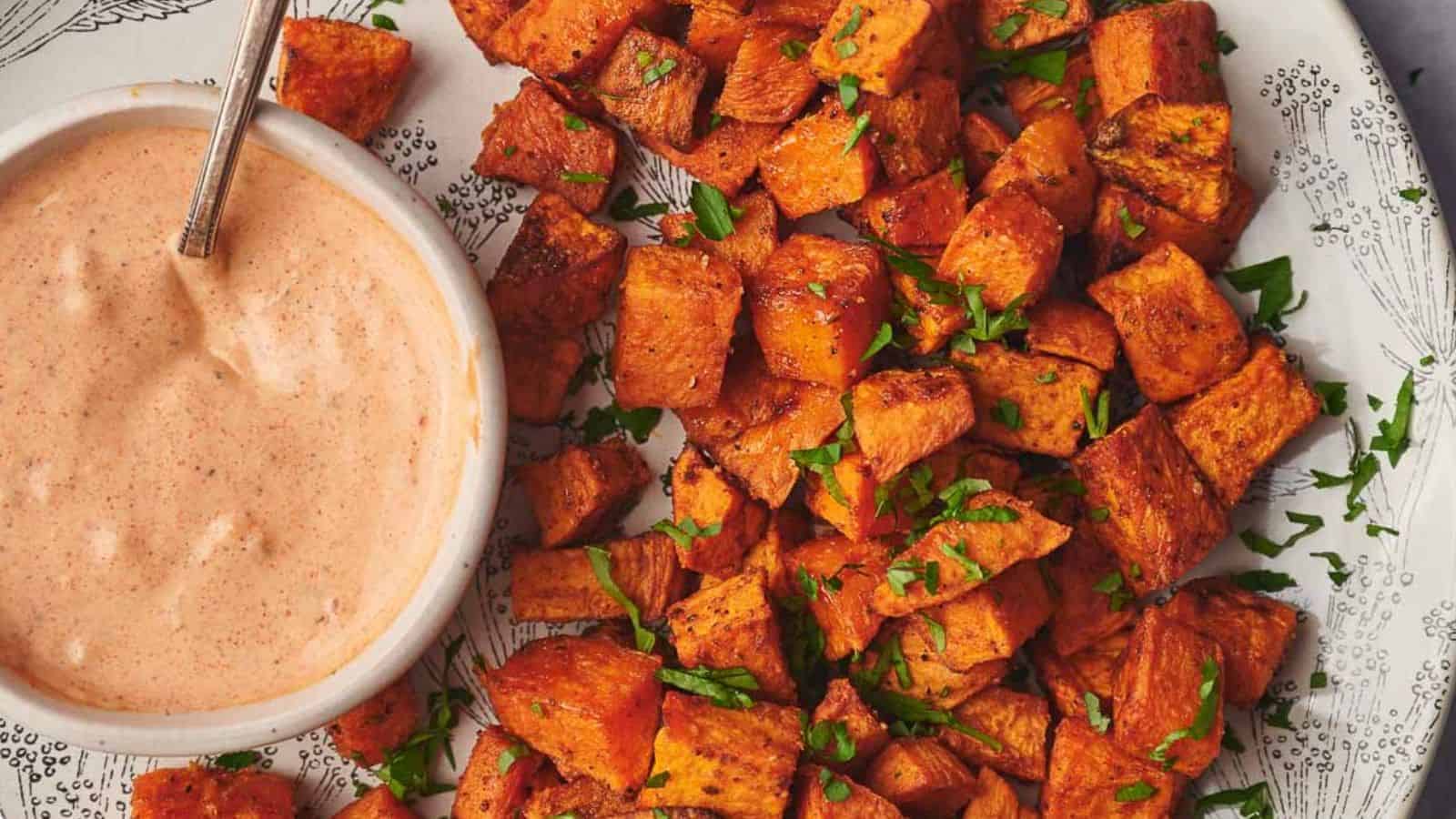 Sweet potato cubes on a plate with a dipping sauce.