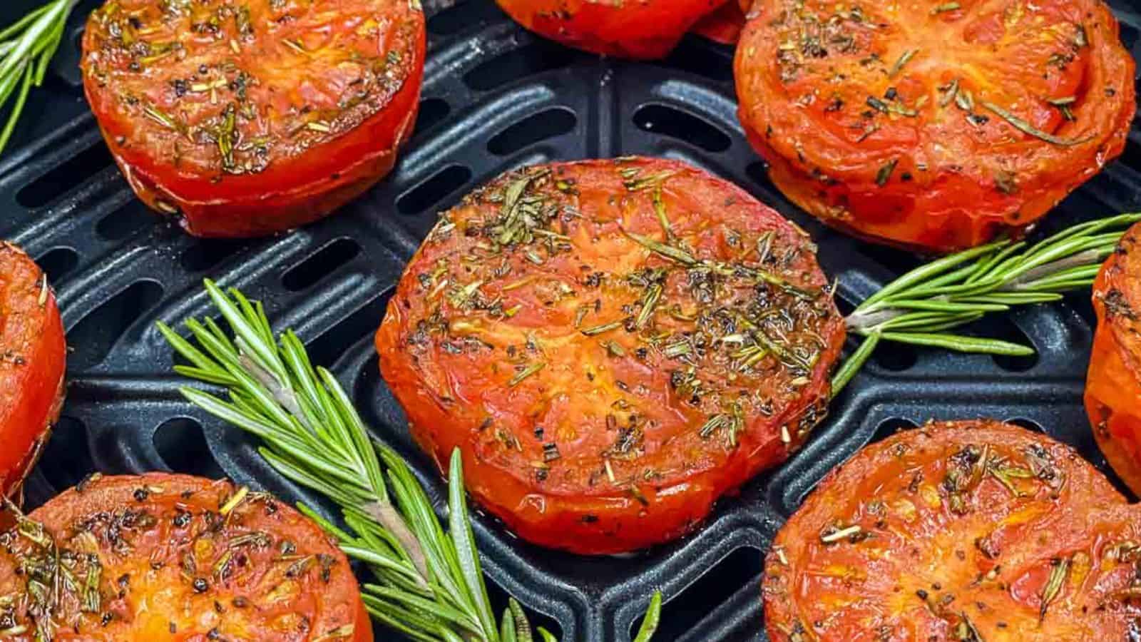 Air fried tomatoes in an air fryer basket with fresh rosemary.
