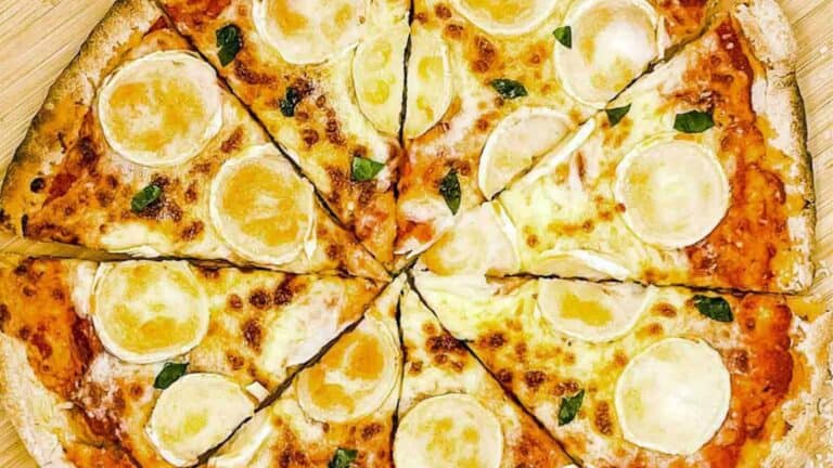 A pizza with cheese cut in half on a wooden board.