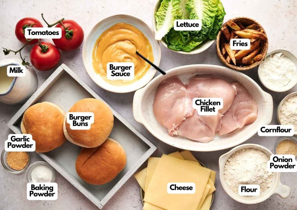 A variety of labeled ingredients, including chicken fillet perfect for a KFC Zinger, burger buns, cheese, vegetables, powders, sauces, and fries arranged on a countertop.