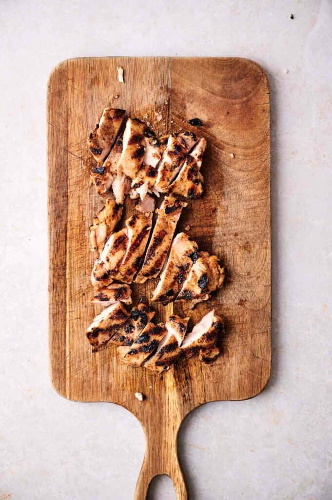Slices of chipotle grilled chicken on a cutting board.