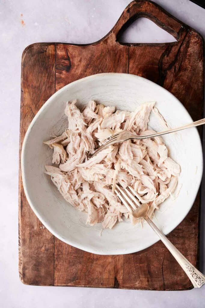 A bowl with shredded chicken and fork.