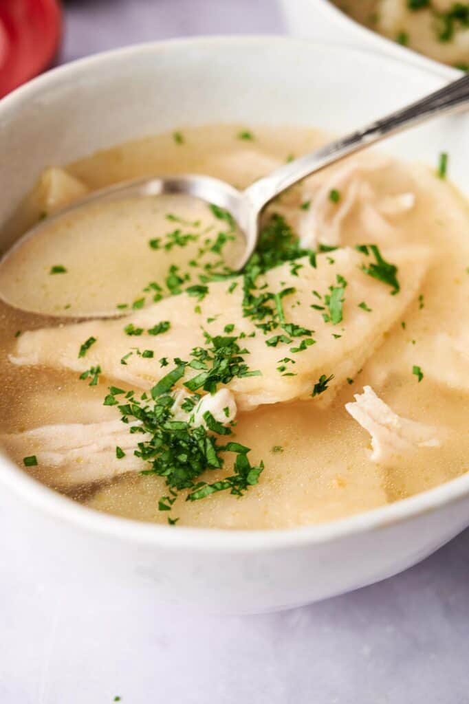 Bowl of Cracker Barrel Chicken and Dumplings soup garnished with herbs.