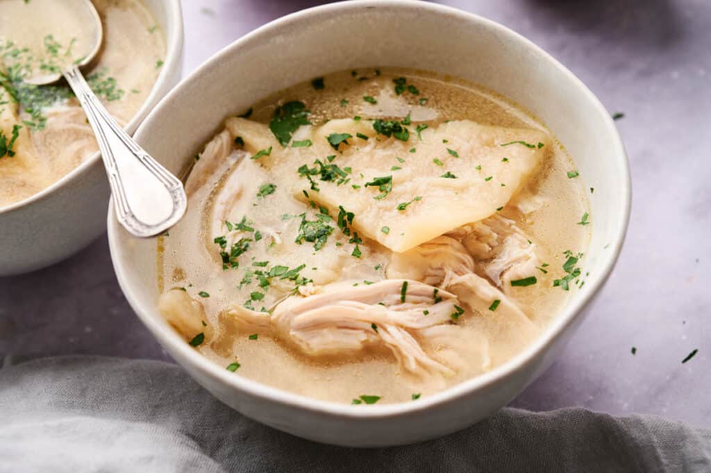 A bowl of Cracker Barrel Chicken and Dumplings soup garnished with parsley.