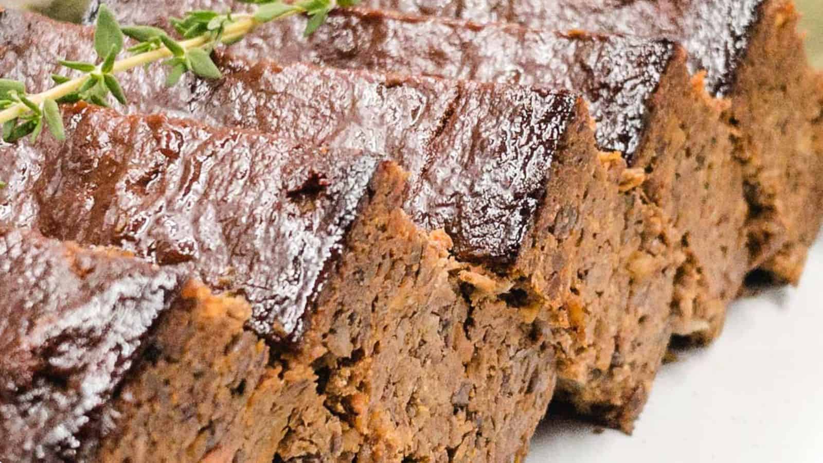 A slice of lentil loaf on a plate with sprigs of thyme.