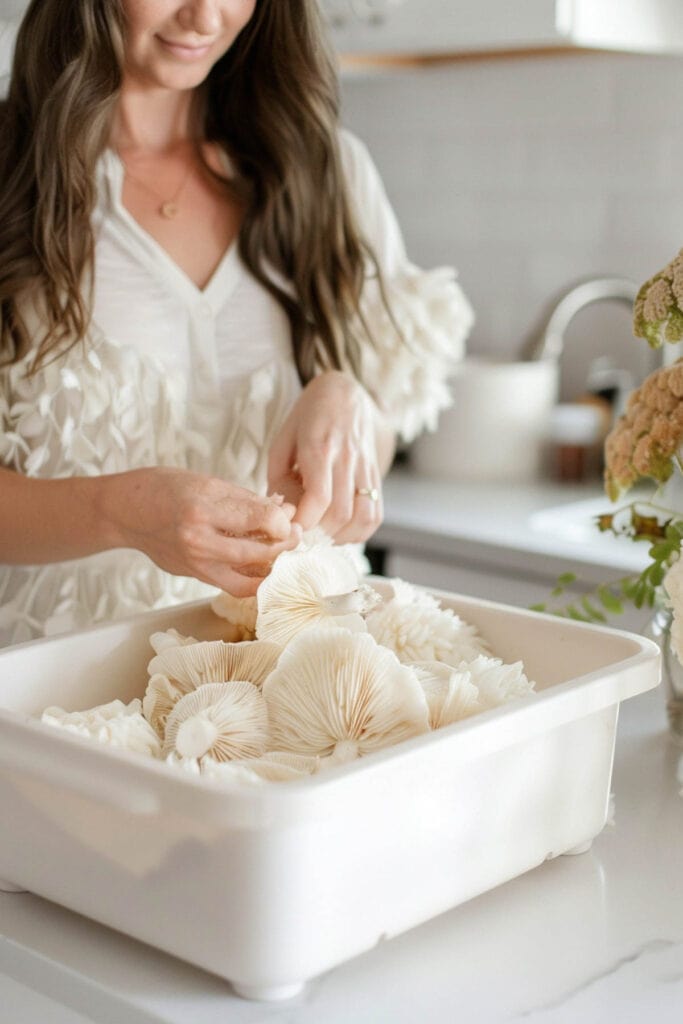 A woman arranging white decorative items in a bowl on a kitchen counter.