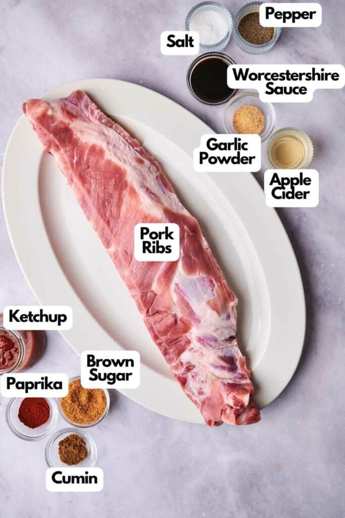 Raw oven-baked pork ribs on a plate with labeled ingredients for seasoning around it.