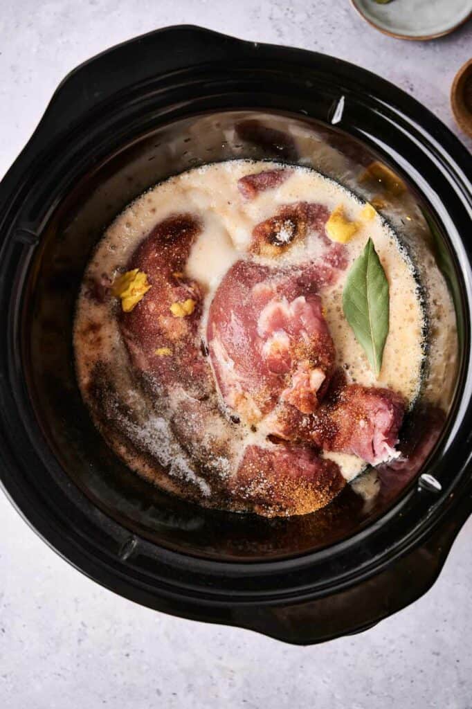 Uncooked pork with spices and liquid in a slow cooker ready for cooking Slow Cooker Pulled Pork.