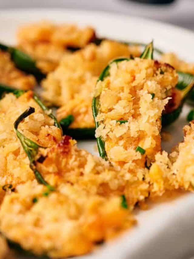 Close-up of crispy, breaded stuffed jalapeños on a white plate.