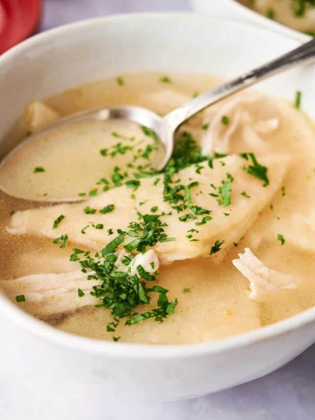 Bowl of Cracker Barrel Chicken and Dumplings soup garnished with herbs.