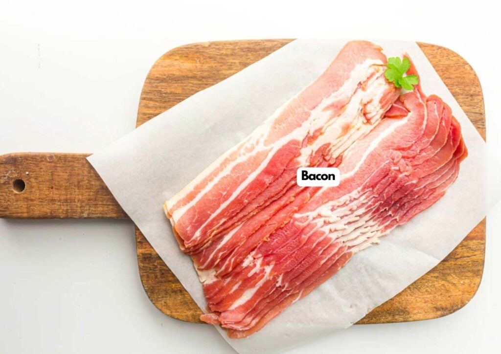 Several strips of raw Bacon are arranged on parchment paper atop a wooden cutting board, with a sprig of parsley for garnish.