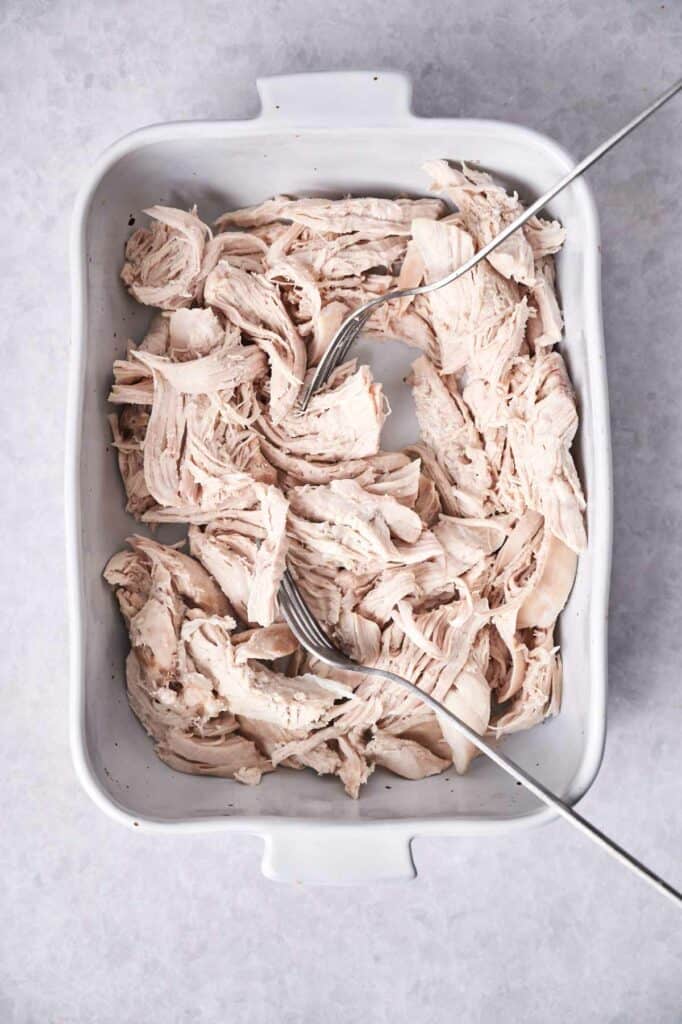 A white baking dish filled with shredded chicken.
