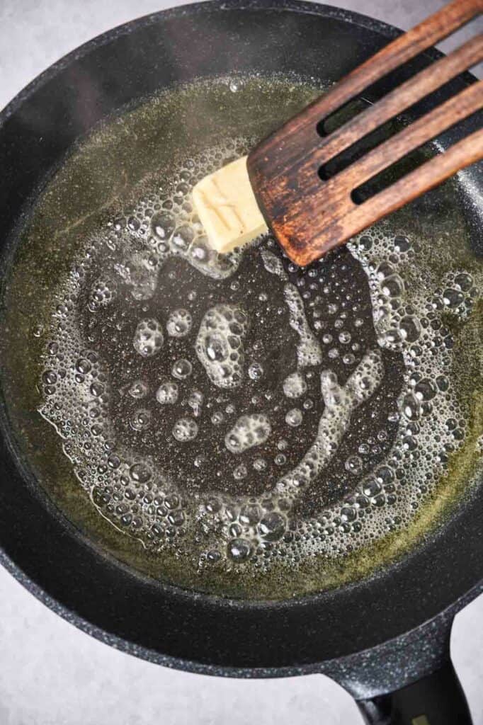 Butter melting in a pan with a wooden spatula for Chicken Pot Pie.