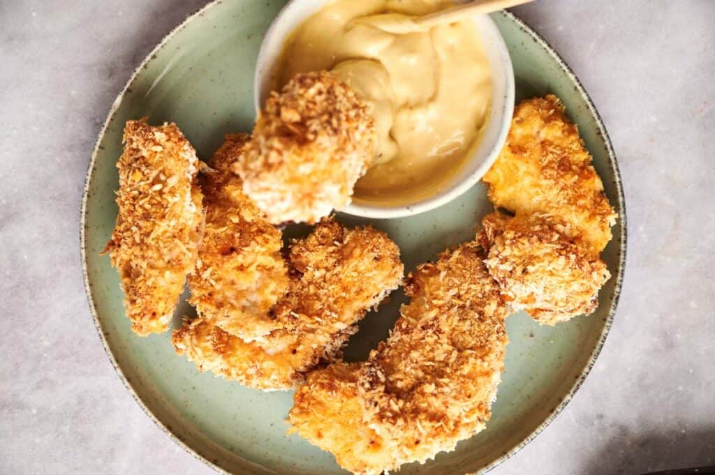 Breaded chicken tenders served with a side of dipping sauce.