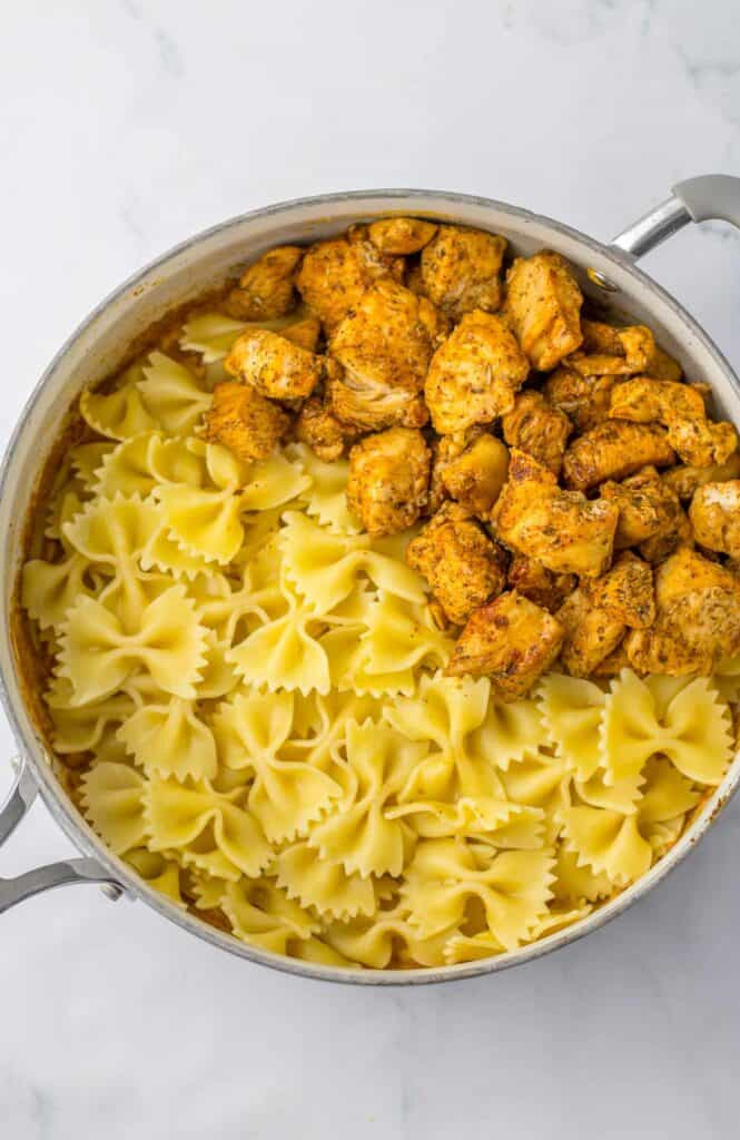 A pot with cooked bowtie pasta and chicken.