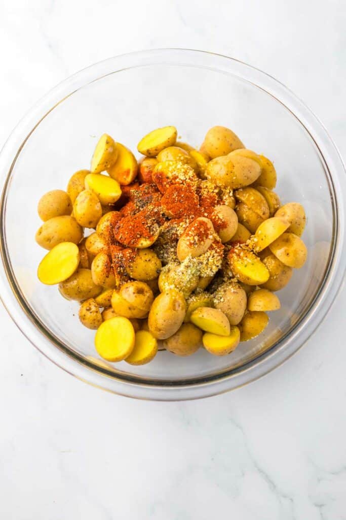 A bowl of baby potatoes seasoned with chipotle and herbs, ready for cooking.