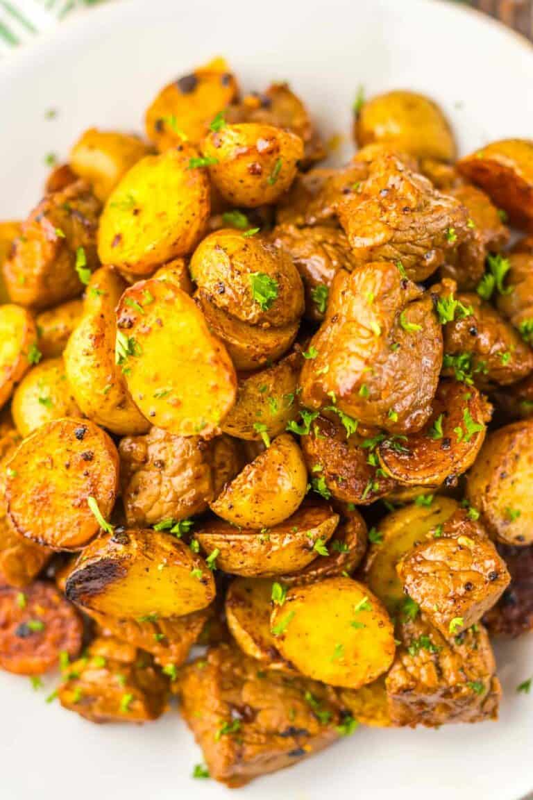 Roasted honey chipotle steak and potatoes garnished with herbs and honey chipotle on a white plate.