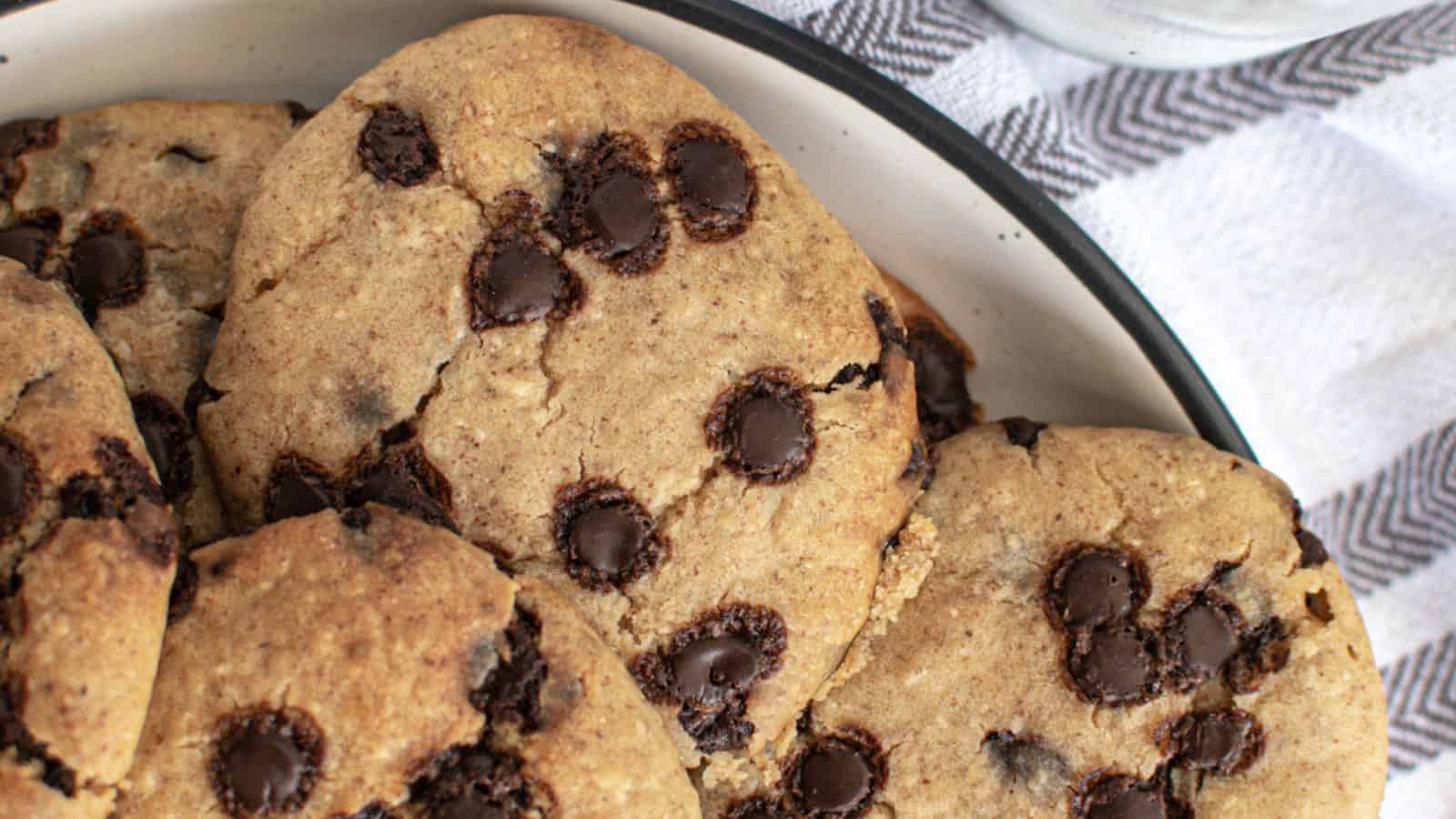 Close-up of freshly baked chocolate chip cookies in a plate, showing the gooey chocolate chunks and golden-brown texture.