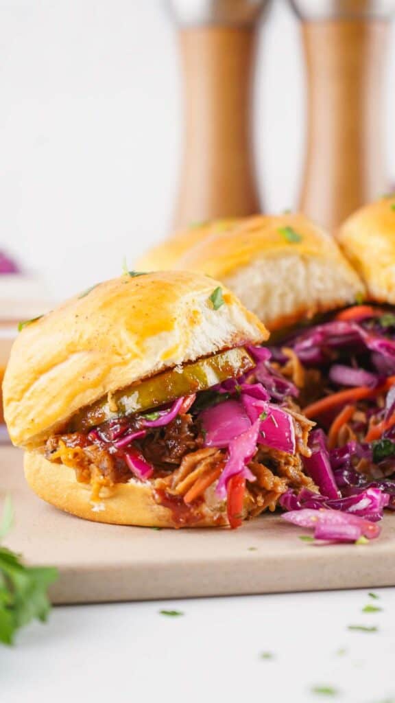 A pulled pork sliders with coleslaw and pickles on a golden bun.