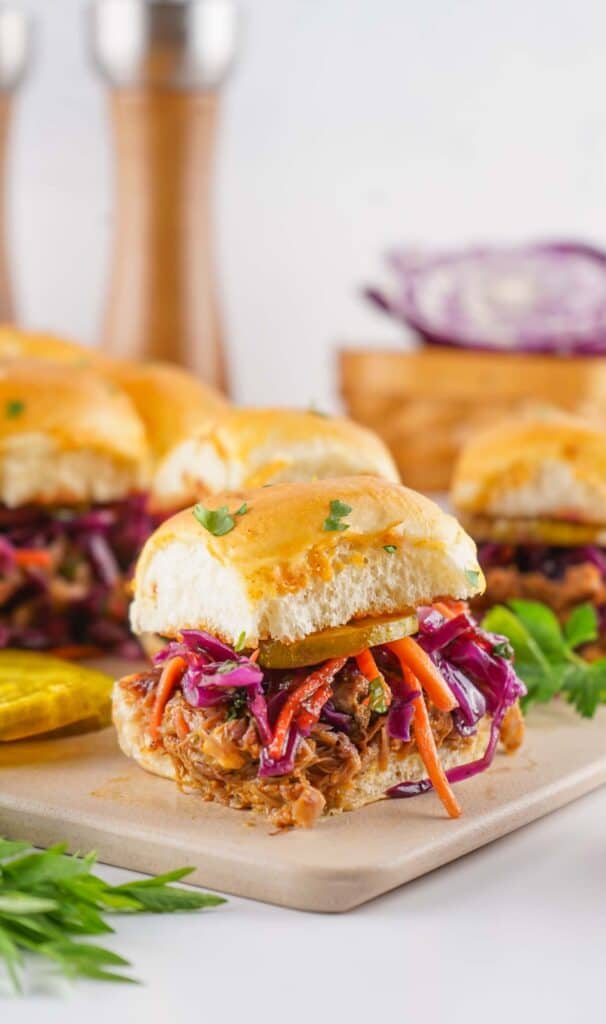 Pulled pork sliders with coleslaw on a serving plate.