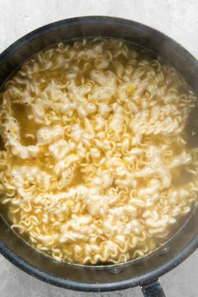 Cooking elevated instant ramen noodles in a pot of boiling water.