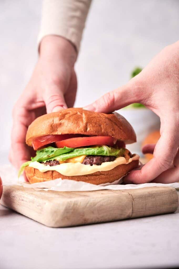 two hands holding a smashed burger