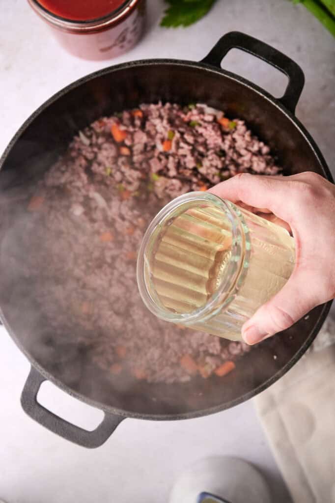 Broth poured into a skillet with ground beef.